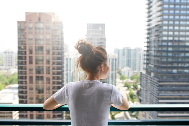 woman looking out from condo balcony
